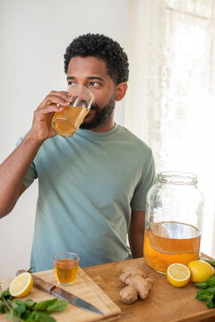 Young black man drinking homemade kombucha drink, flavoured with lemon and mint, healthy drink, organic probiotic beverage
