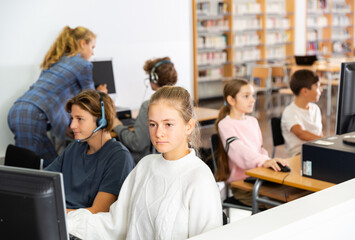 Obraz premium Teenager girls and boys studying in computer lab in library.