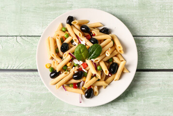 Plate with tasty pasta salad on light wooden background