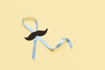 Light blue awareness ribbon with black paper mustache on color background