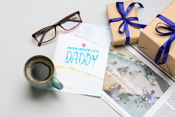 Composition with greeting card, newspaper, eyeglasses, cup of coffee and gifts for Father's Day celebration on white background