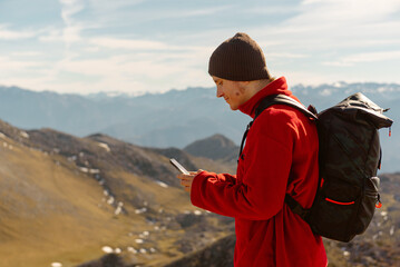 White male mountaineer, with a backpack, using a GPS application on his smartphone to orient himself in the mountains. caucasian man using the mobile in the mountain.