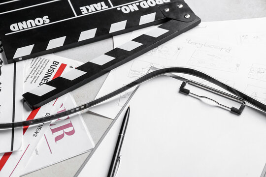 Clipboard with film, newspapers and movie clapper on light background