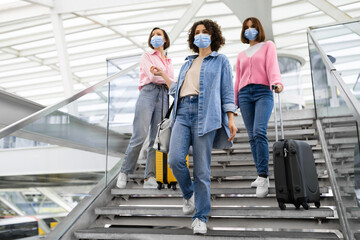 Fototapeta na wymiar Group Of Women Wearing Protective Face Masks Walking On Stairs At Airport