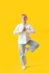 Mature woman meditating on yellow background