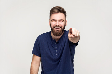 Amused handsome man laughing out loud, pointing finger to camera, indicating ridiculous idiot.