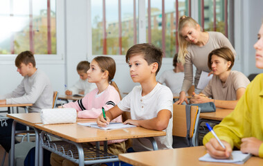 Group of teenage girls and boys exercising during lesson in classroom.