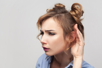 Woman trying to overhear someone, holding hand near ear, tries to understand words eavesdropping.