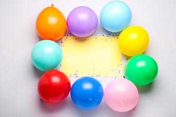 Frame made of colorful balloons and serpentine with blank paper sheet on grey background