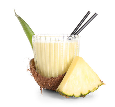 Glass of tasty pineapple smoothie with straw in coconut shell on white background
