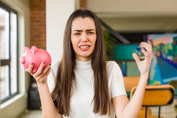 pretty young woman with a piggy bank. savings concept. house interior design