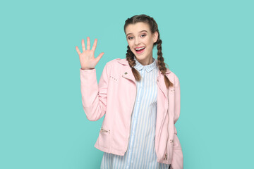 Friendly lovely teenager girl waving hand, saying hello or bye, looking at camera with happiness.