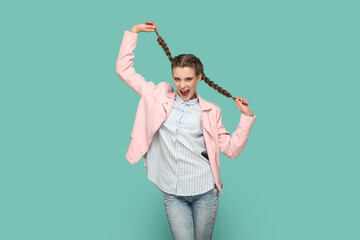 Excited amazed teenager girl having fun, pulling her pigtails, looking at camera with smile.