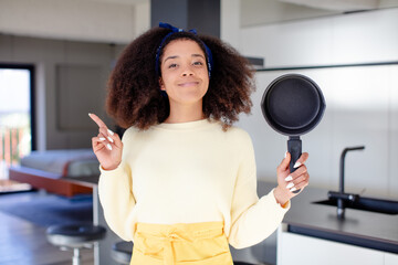 pretty afro black woman smiling cheerfully, feeling happy and pointing to the side. home chef concept