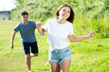 Obraz premium Young man and girl are running on the grass together
