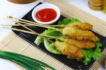 Sempol ayam or fried chicken satay, one ofpopular street food in Indonesia.  Served with chili sauce. White marble background.