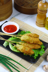 Sempol ayam or fried chicken satay, one ofpopular street food in Indonesia.  Served with chili sauce. White marble background.