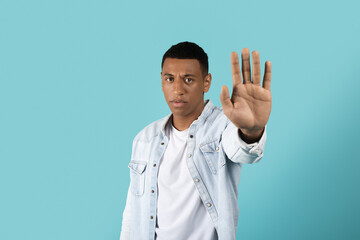 Sad angry serious confident millennial black guy in casual showing hand stop sign