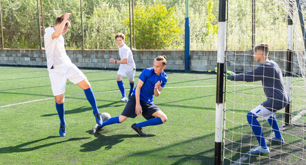 Junior football teams having golmouth scramble and struggling for ball