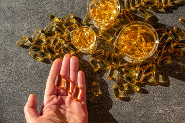 Fish oil capsules in hand on a slate background in hard light with shadows.omega fatty acids....