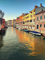 Central Venice, historic houses reflected in canal on a sunset, toned image. Get lost in the maze-like streets and admire the beautiful buildings, canals, and bridges.