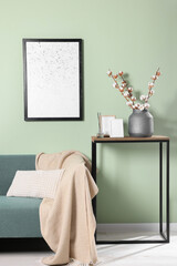 Branches with white fluffy cotton flowers on console table in cozy room. Interior design
