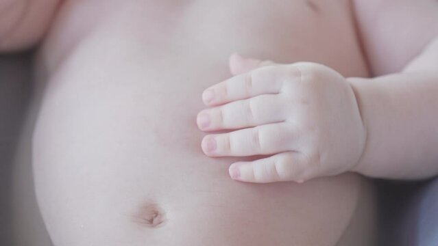 Baby's arm resting on belly in bathtub cute Caucasian white newborn fingers playful mood