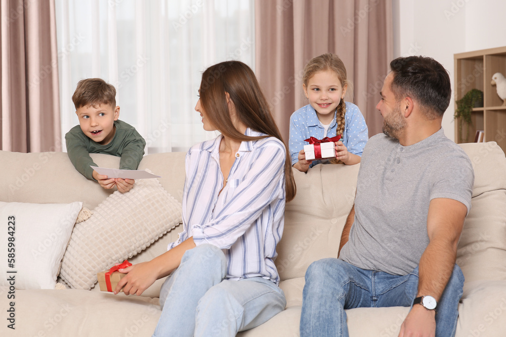 Sticker Cute little children presenting their parents with gifts on sofa at home