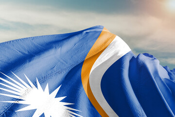 Marshall Islands national flag cloth fabric waving on beautiful grey sky.