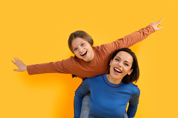 Family Fun. Cheerful Little Girl And Her Mom Playing Over Yellow Background