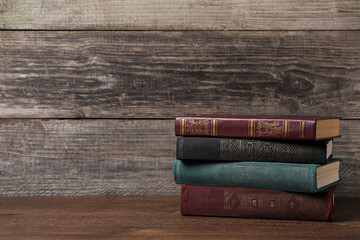 Stack of old hardcover books on wooden table, space for text