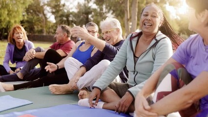 Happy senior people after yoga sport class having fun sitting outdoors in park city - Elderly community and summer concept - Powered by Adobe
