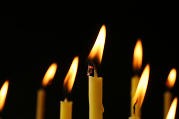 Burning church candles on black background, closeup