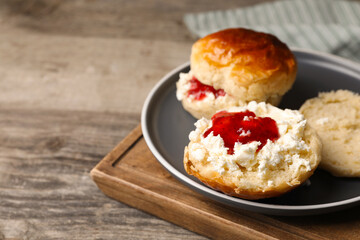 Freshly baked soda water scones with cranberry jam and butter on wooden table, closeup. Space for...
