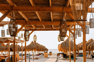 Bamboo lanterns hang from the thatched roof. In the background, next to the pontoon that leads to...