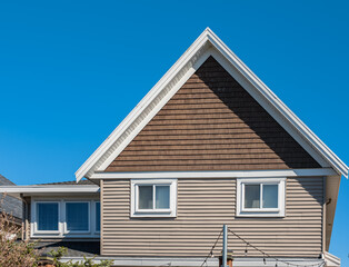 Top of a house with nice windows in the blue sky background. Beautiful Home Exterior. Real Estate Exterior Front House