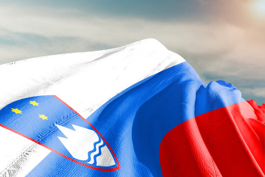 Slovenia national flag cloth fabric waving on beautiful grey sky.