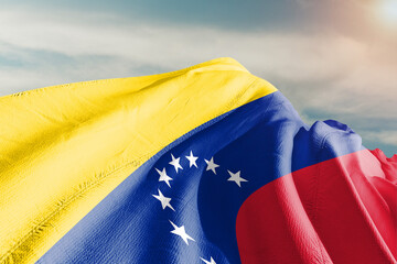 Venezuela national flag cloth fabric waving on beautiful grey sky.