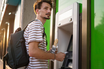 Fototapeta na wymiar side view man use ATM machine to withdraw money with credit card
