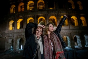 Fototapeta premium Beautiful mother and daughter enjoying themselves in the evening at the Roman Colosseum