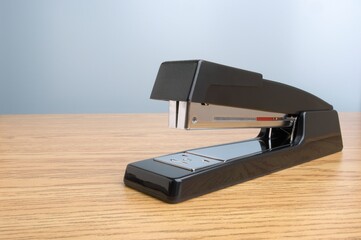 Close-up shot of a stapler on a wooden table - obrazy, fototapety, plakaty
