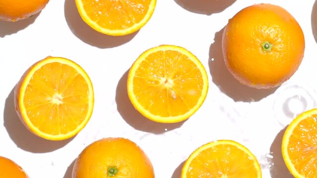 Top view of the cut and whole fresh orange in the water on a white background