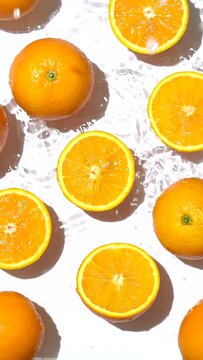 Top view of the cut and whole fresh orange in the water on a white background