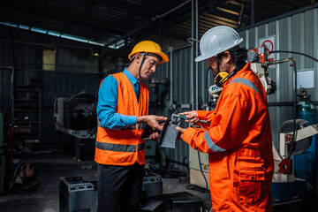 Engineer team service robot welding working in automation factory. People worker in safety suit work robotic arm software programming or replacing part in automated manufacturing industry technology.