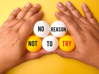 Hand holding ping pong ball with the word NO REASON NOT TO TRY. Business concept.