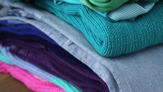 A stack of clothes in different colors. The concept of conscious clothing consumption.