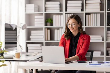 Young latin professional business woman office worker analyst sitting at desk working on laptop...