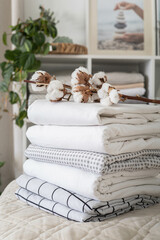 Fototapeta na wymiar Cotton branch with pile of folded bed sheets and blankets