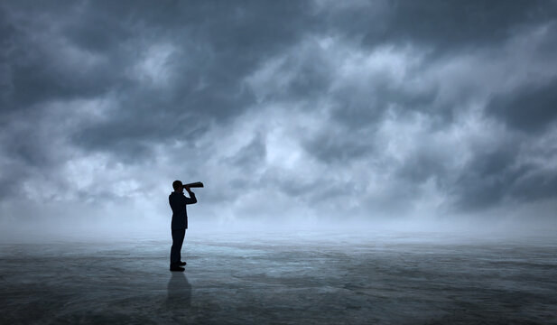 Businessman Looking At Binoculars in wide Empty Space. Business Man Vision, Perspective and Future Planning Concept. The person Stands on Ground  with Infinity Dramatic sky clouds 