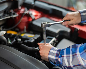 Fototapeta na wymiar Female auto mechanic unscrewing a nut to replace a car spark plug.